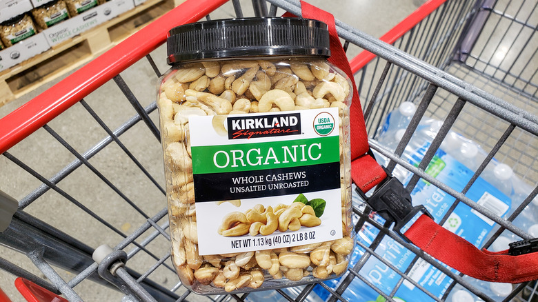 Container of Kirkland Signature Cashew Nuts sitting in shopping cart