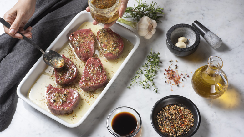 Steaks being marinated in a white casserole dish