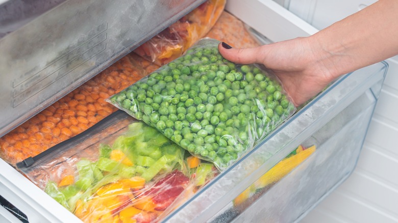 Hand grabbing frozen peas