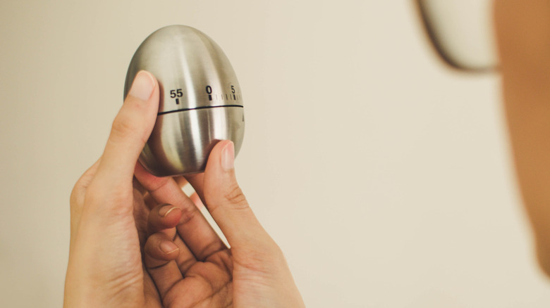 Hands holding an egg timer