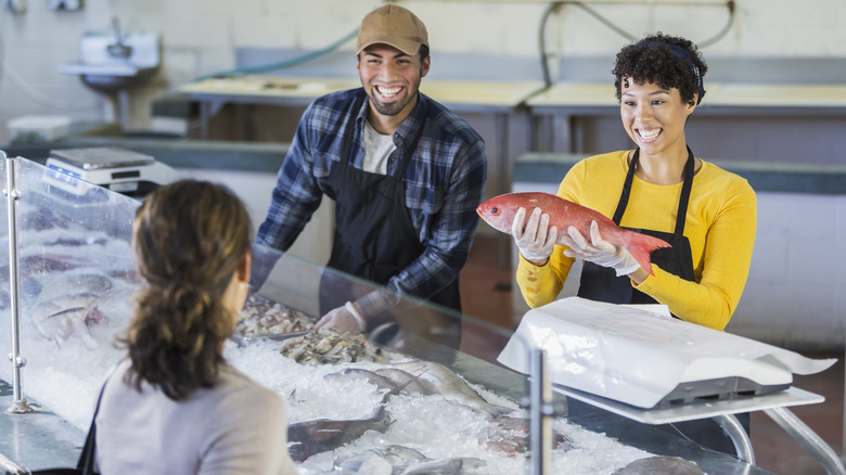 fishmongers showing customer a fish