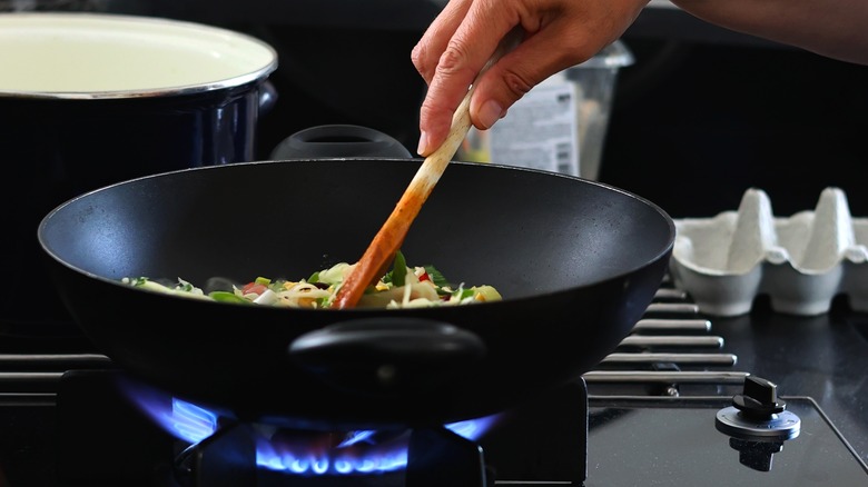 Person using wok over gas stove