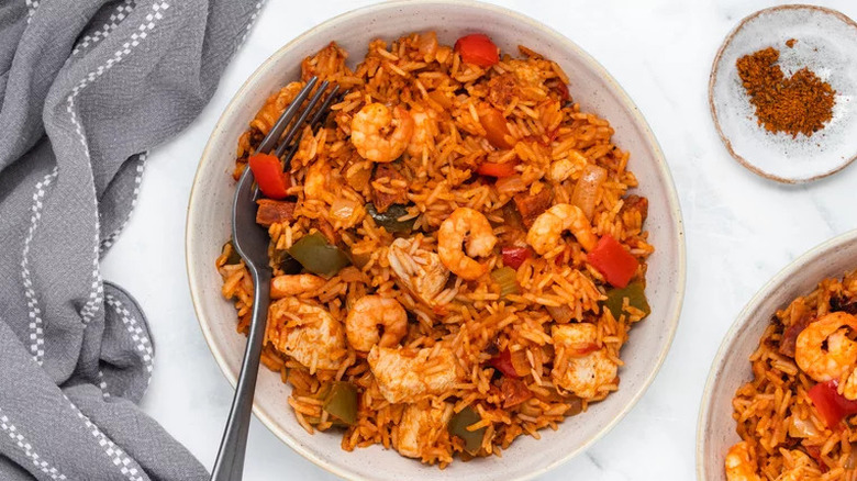 Hearty jambalaya in bowl with spices and linens 