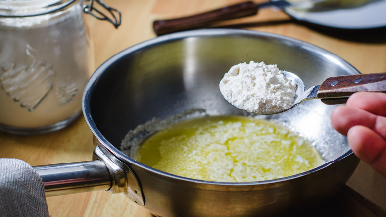 adding flour to butter to make roux