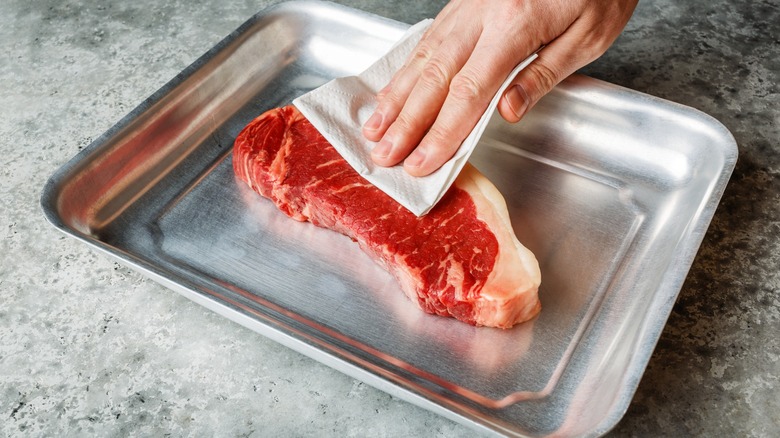 hand patting dry a steak 