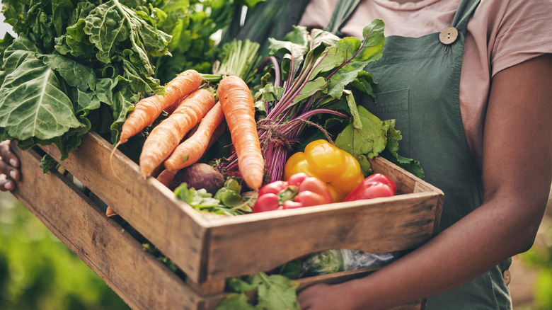 Person holding wooden crate of fresh produce