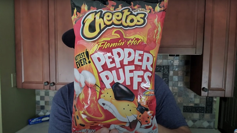 Bag of Flamin' Hot Pepper Puffs held up in a kitchen