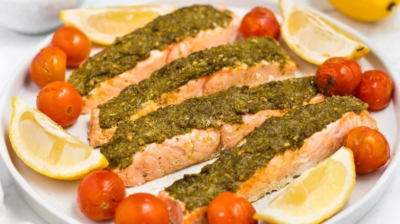 Pesto baked salmon with lemon wedges