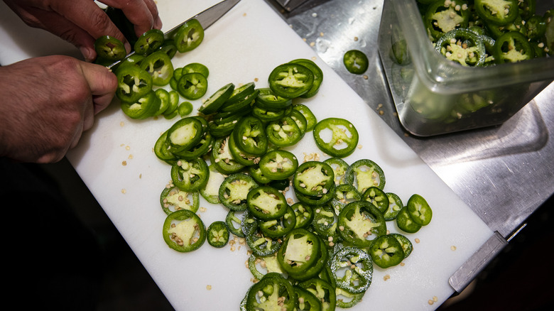 man cutting jalapenos on board