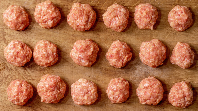 Balls of raw ground beef on a wooden board