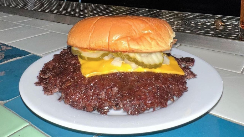 Smash burger in a bun at Burger She Wrote with onions and pickles