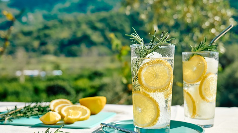  glasses, sugar, ice water and fresh lemons on a table