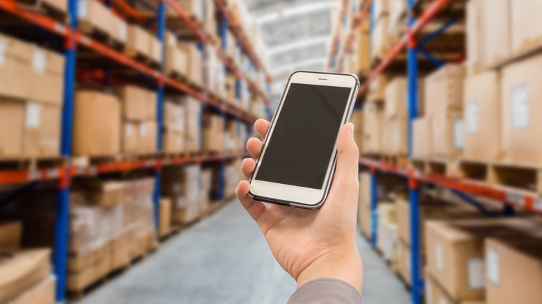 Hand holding a smartphone in warehouse