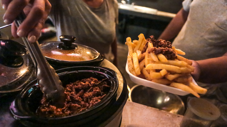 hands holding french fries by toppings