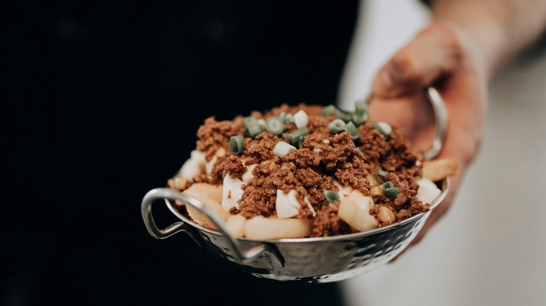 person holding specialty poutine