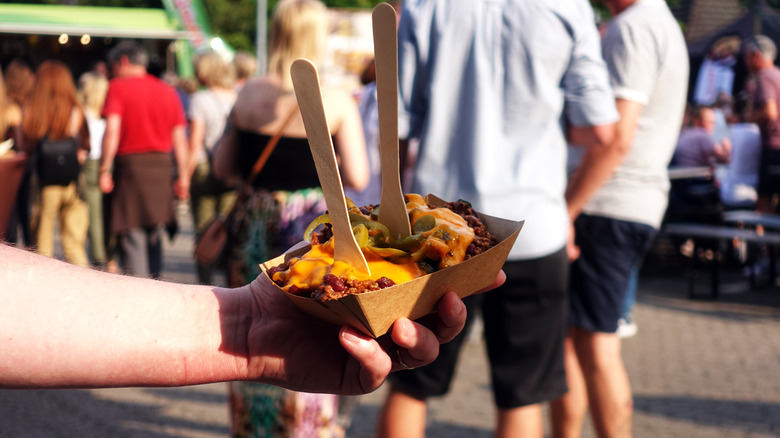 person holding poutine on street