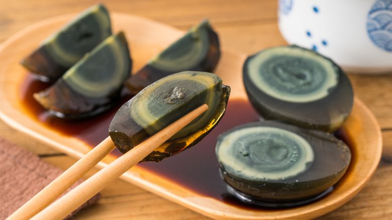 Sliced century egg in chopsticks