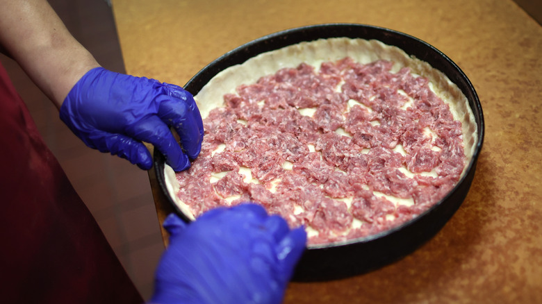 cook making deep dish pizza