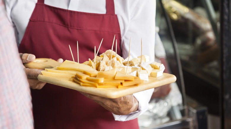 Man holding samples of cheese on a cutting board