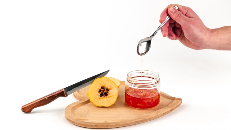 holding spoon over quince jam