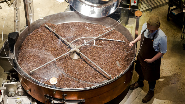 person handling coffee roaster machine