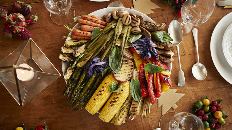 An assortment of grilled vegetables on a platter at a table set for Christmas dinner