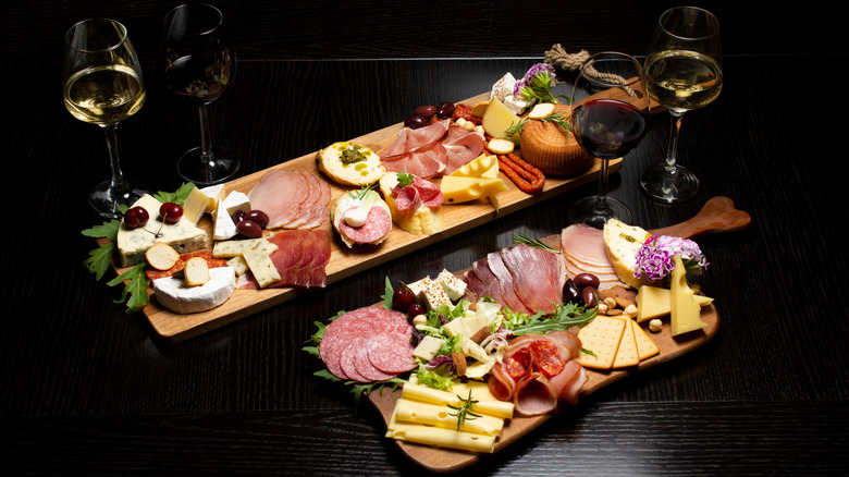 two fancy charcuterie boards with meats, cheeses, and glasses of wine