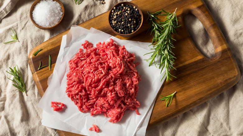 ground beef on wood board with fresh herbs