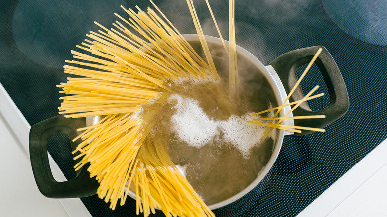 cook adding salt to cooking pasta