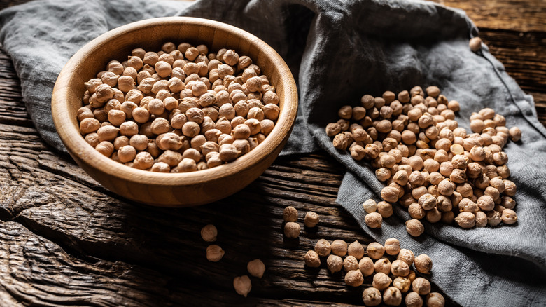 Chickpeas in a wooden bowl next to a towel