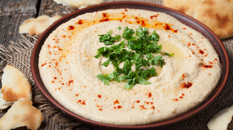 Hummus in a ceramic bowl with parsley garnish