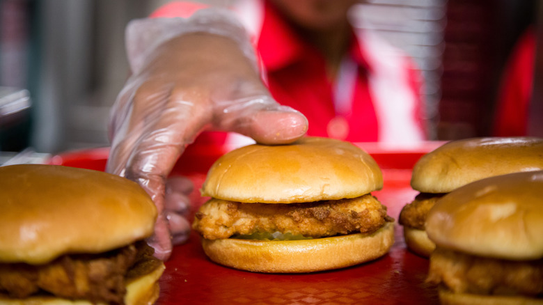 a chick fil a employee reaching for a chicken sandwich