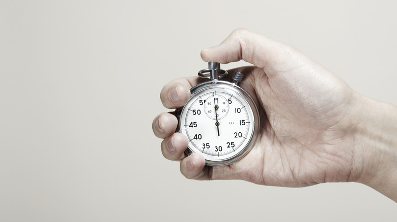 hand holding a silver stop watch