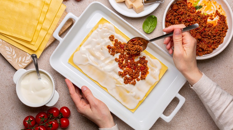 cook making lasagna with ingredients