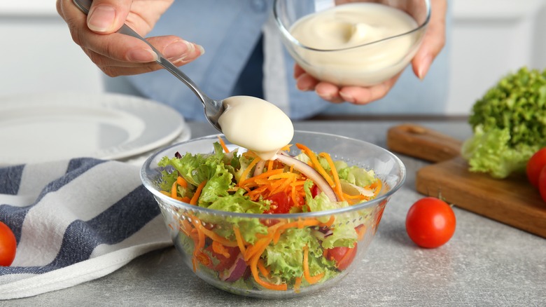 person scooping dressing onto salad