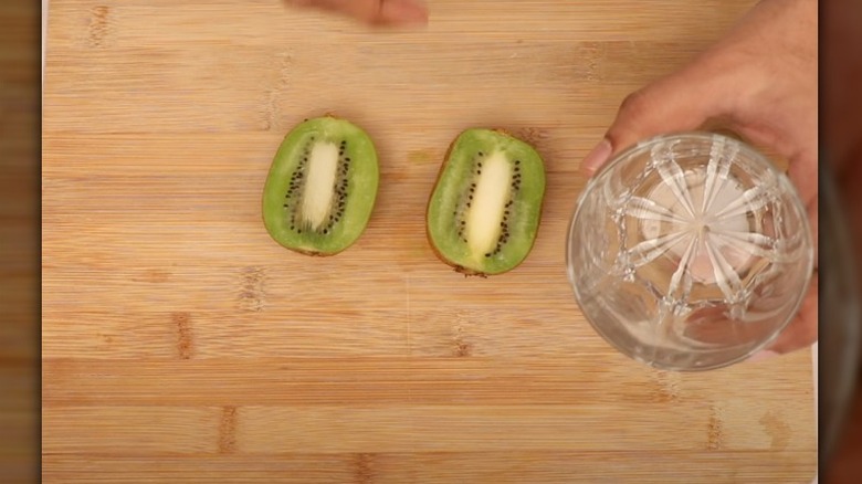 kiwi on cutting board with glass cup