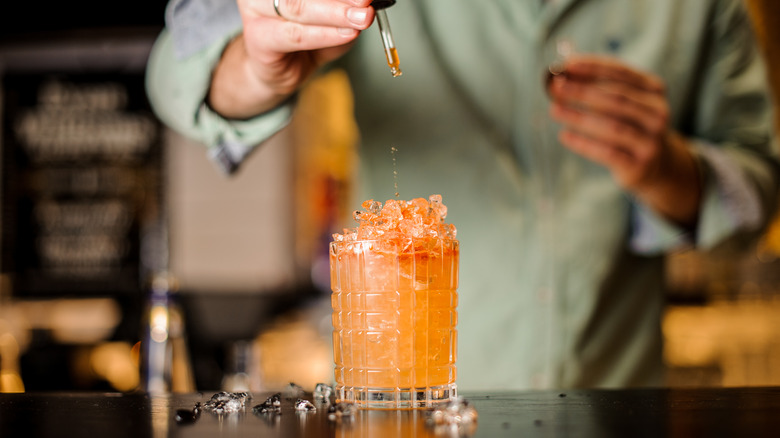 bartender adding drops of bitters to drink