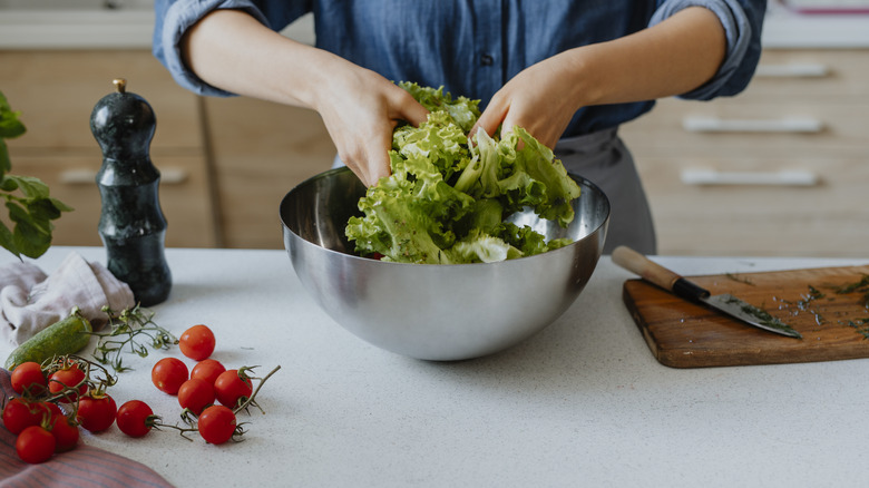 Person tossing salad with hands