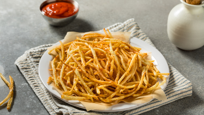 A large plate of fresh shoestring fries, with a ramekin of ketchup