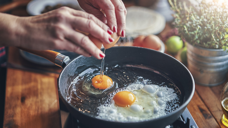 Person cracking eggs into pan