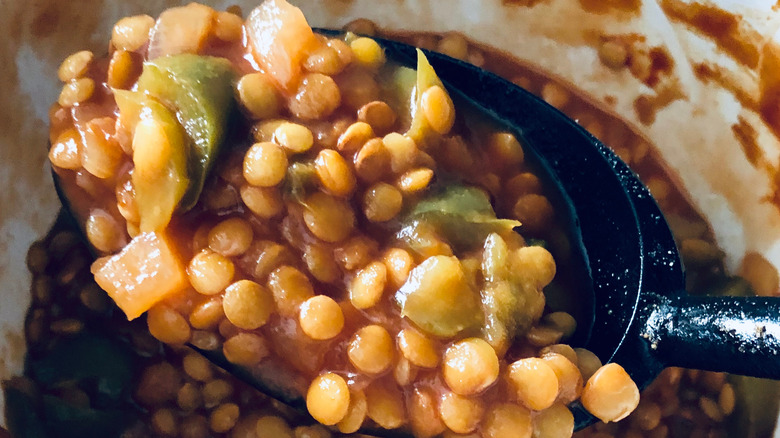 lentils and peppers in a black serving spoon