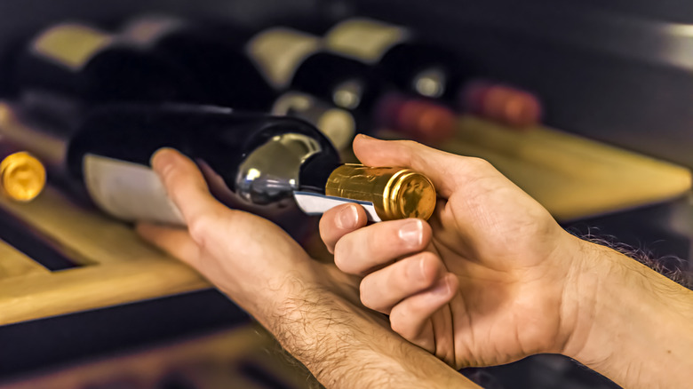 hands with horizontal wine bottle