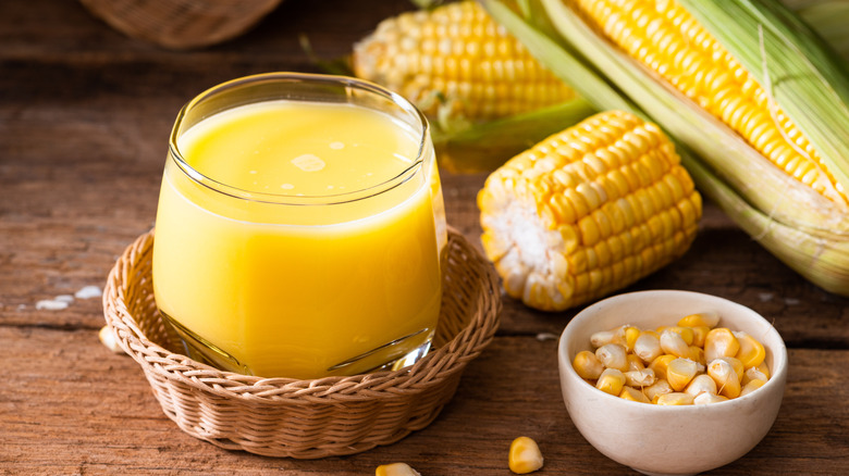 glass of corn milk in a basket with corn on the cob