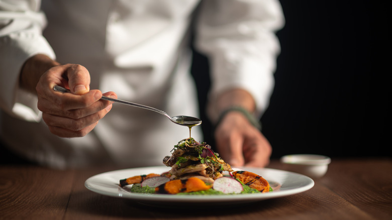 A chef applying sauce to a dish