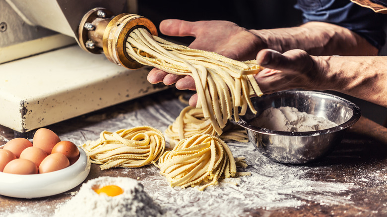 hands making pasta, egg in foreground