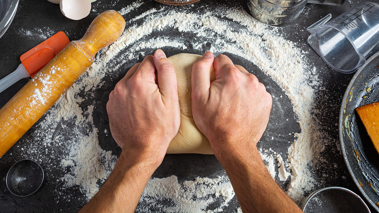 Dough with rolling pin and hands