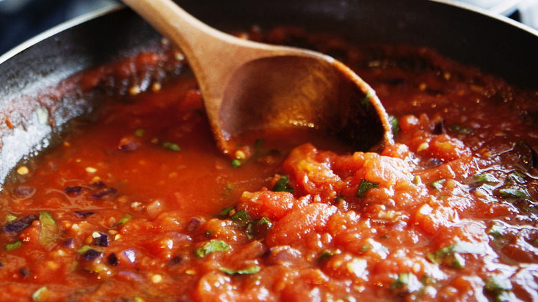 stirring tomato sauce with wooden spoon