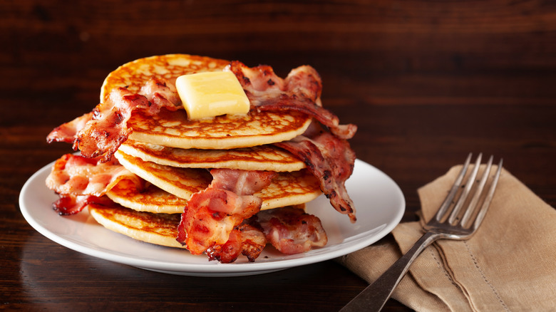 pancakes and bacon on plate with butter pat