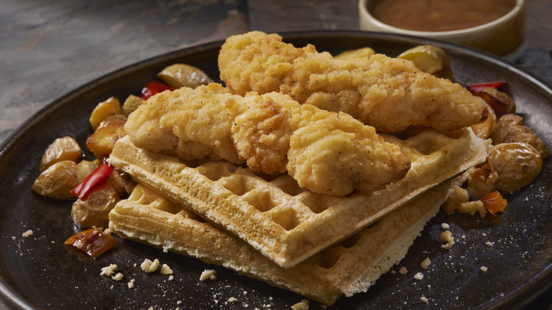 Chicken tenders and waffles with potatoes on plate