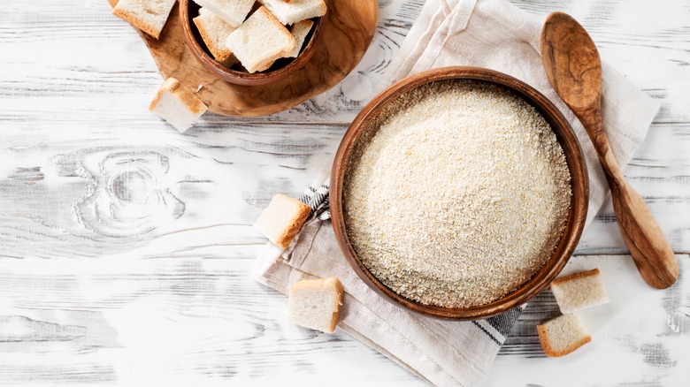 Breadcrumbs in a bowl on wood table with spoon